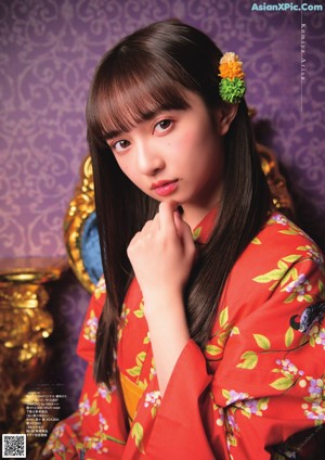 A woman in a red kimono standing in front of a window.