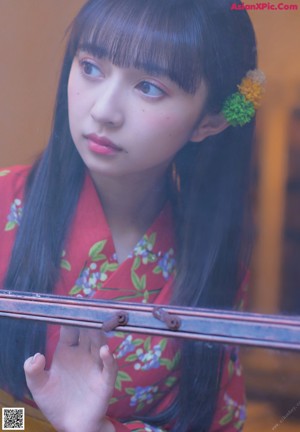 A woman in a red kimono standing in front of a window.