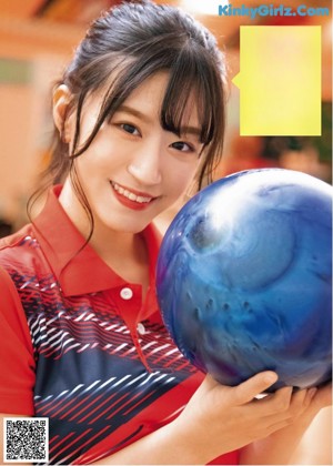 A woman in a blue shirt and white skirt holding a bunch of bowling balls.