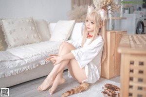 A woman sitting on top of a white couch next to a cat.