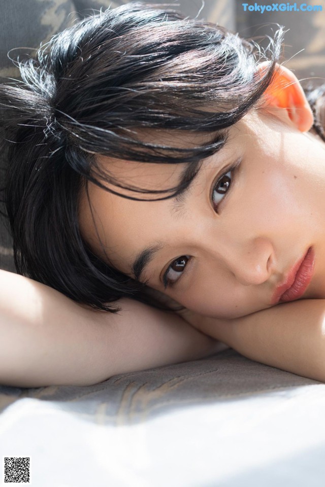 A young woman laying on a bed with her head resting on her hands.