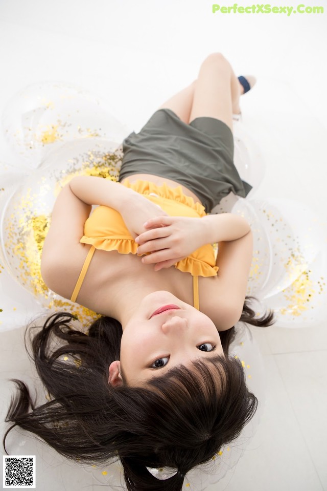 A woman laying on the floor in a yellow dress.