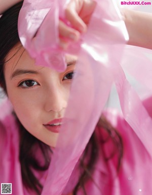 A girl with long black hair wearing a pink shirt.