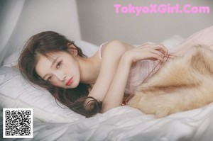 A woman in a pink lingerie posing on a bed.