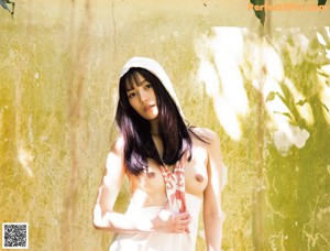 A woman in a white dress standing under a tree.