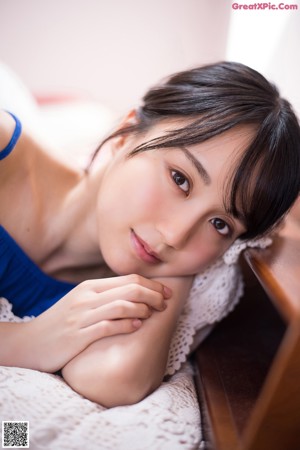 A woman in a blue off the shoulder top holding a cactus.