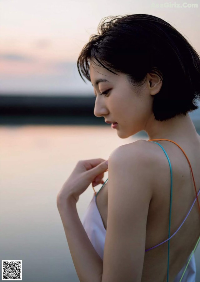 A woman in a white dress standing by the water.