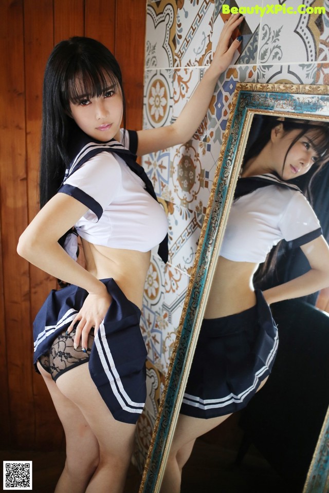 A woman in a school uniform leaning against a mirror.