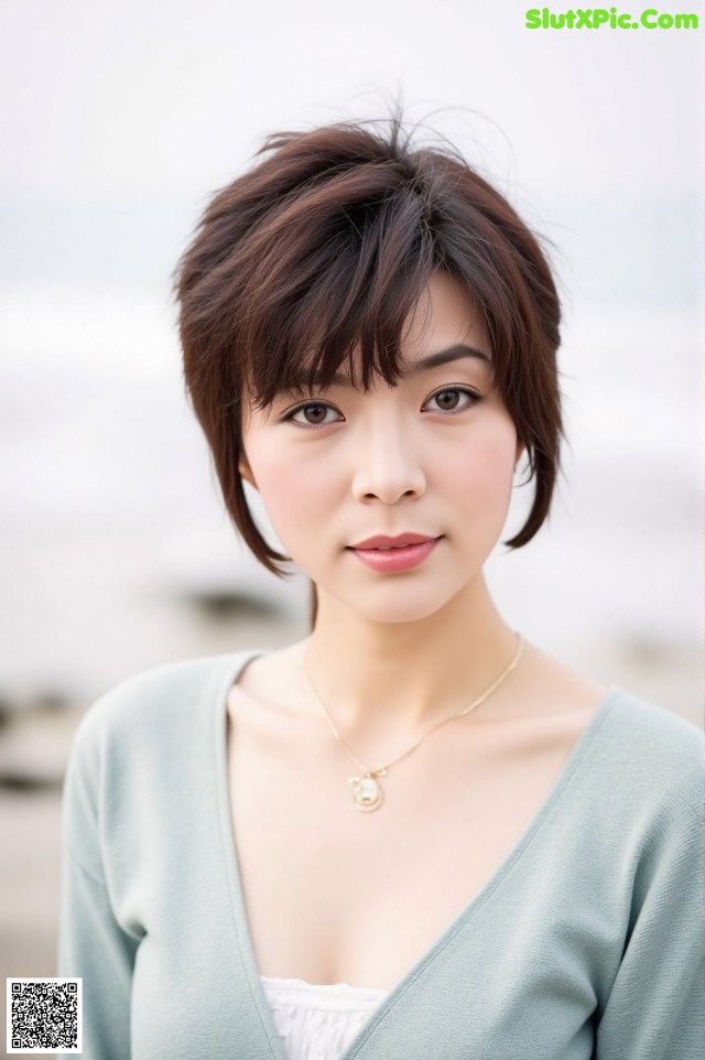 A woman wearing a green cardigan and a necklace.