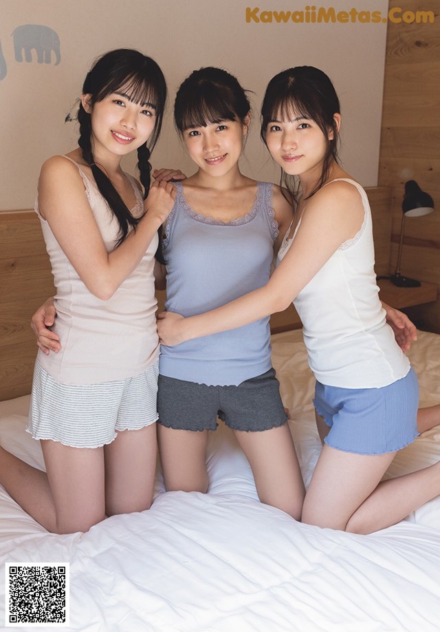 A group of three women sitting on top of a bed.
