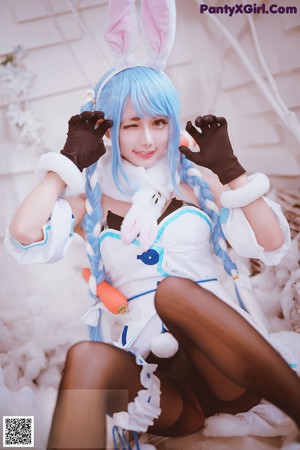 A woman in a bunny costume is sitting in the snow.