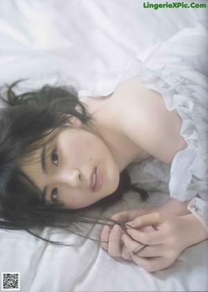 A woman laying on a bed in a white dress.