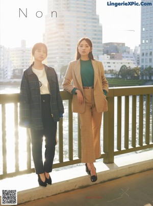 Two young women standing next to each other on a bridge.