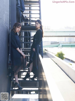 Two young women standing next to each other on a bridge.