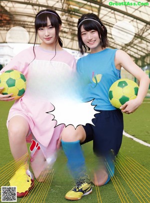 Two young women posing for a picture with soccer balls.