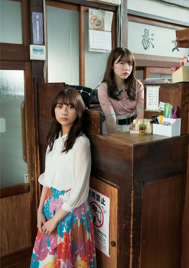 Two young women standing next to each other in front of a counter.