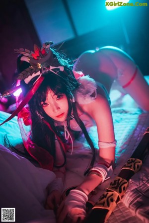 A woman in a red and white lingerie sitting on a bed.