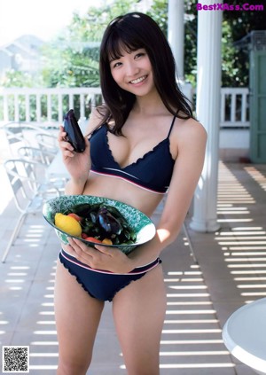 A woman in a blue bikini and a green hat.