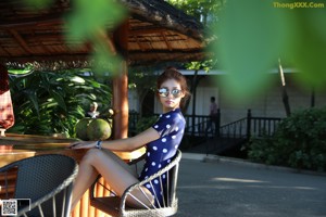 A woman sitting on a lounge chair next to a swimming pool.