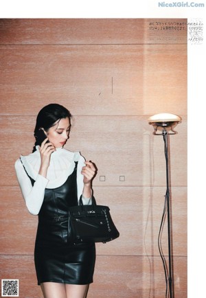 A woman in a black coat and pink shoes sitting on a chair.