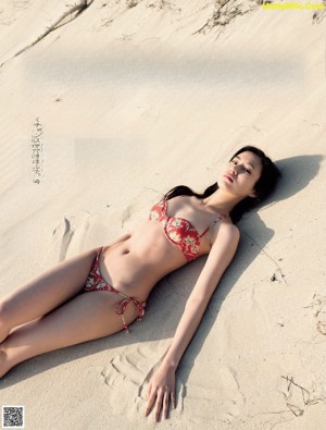 A woman in a white dress is posing on the beach.