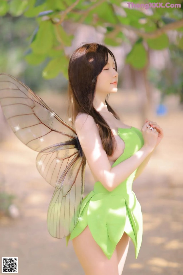 A woman in a green dress with a fairy wings.