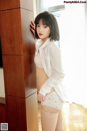 A woman in a white shirt and panties posing for the camera.