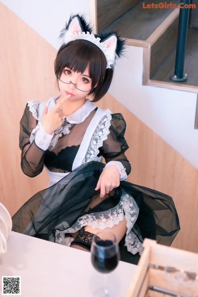 A woman in a black and white dress sitting at a table.