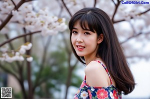 A woman in a yellow floral dress poses for a picture.