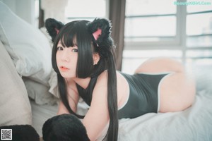 A woman laying on a bed with a black cat tail.