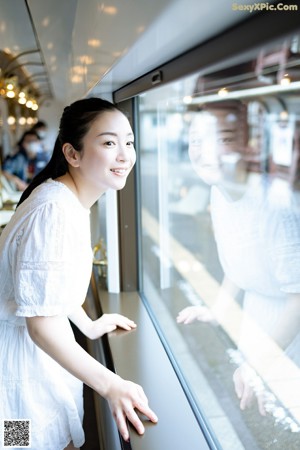A woman in a white dress standing next to a train.