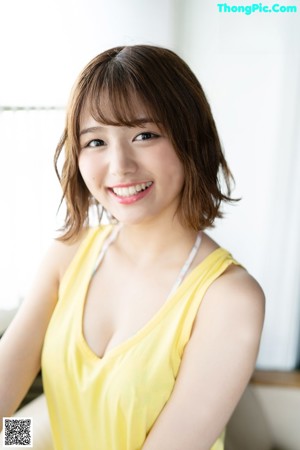 A woman in a yellow tank top posing for a picture.