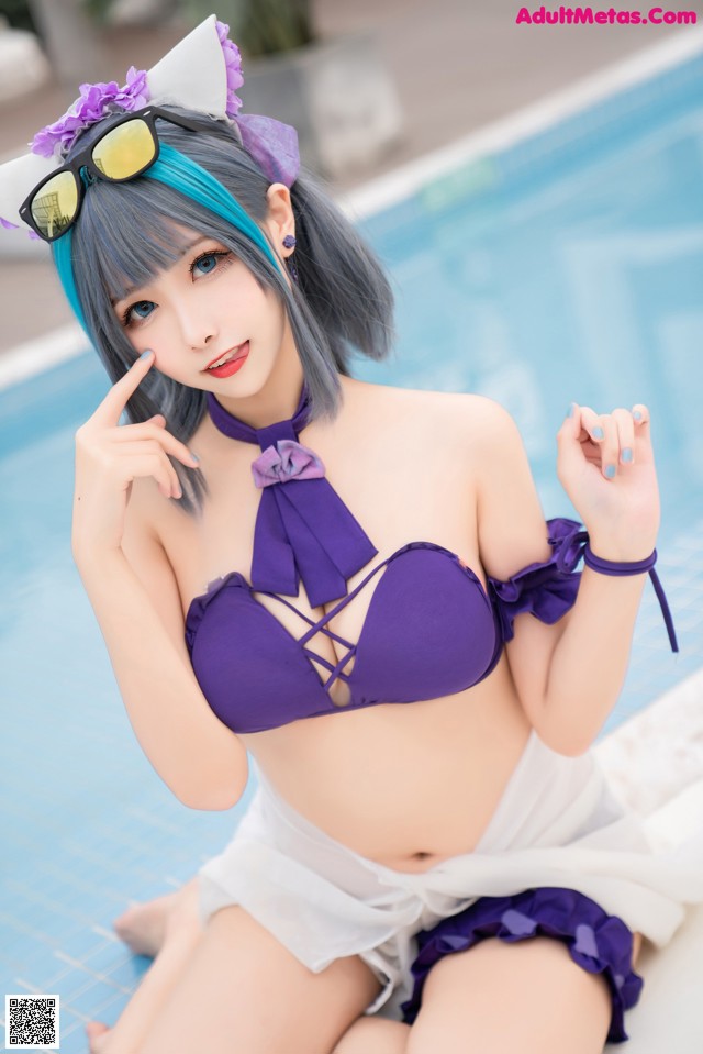 A woman in a purple bikini sitting by a pool.