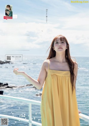 A woman in a yellow dress standing on a pier.