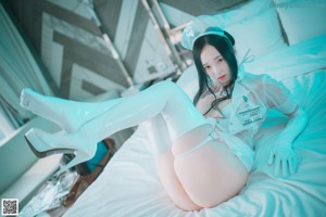 A woman in a white nurse outfit sitting on a bed.