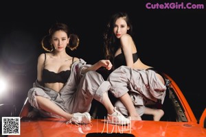 A couple of women sitting on top of a car.