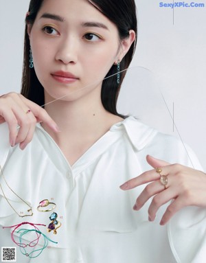 A woman in a white dress sitting on a black background.