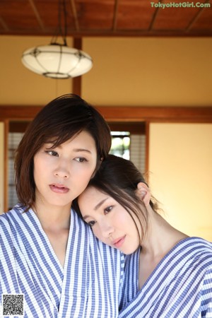 A woman in a blue and white striped robe looking at herself in the mirror.