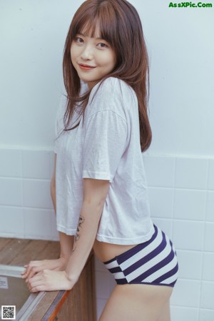 A woman in a white shirt and striped panties posing for a picture.